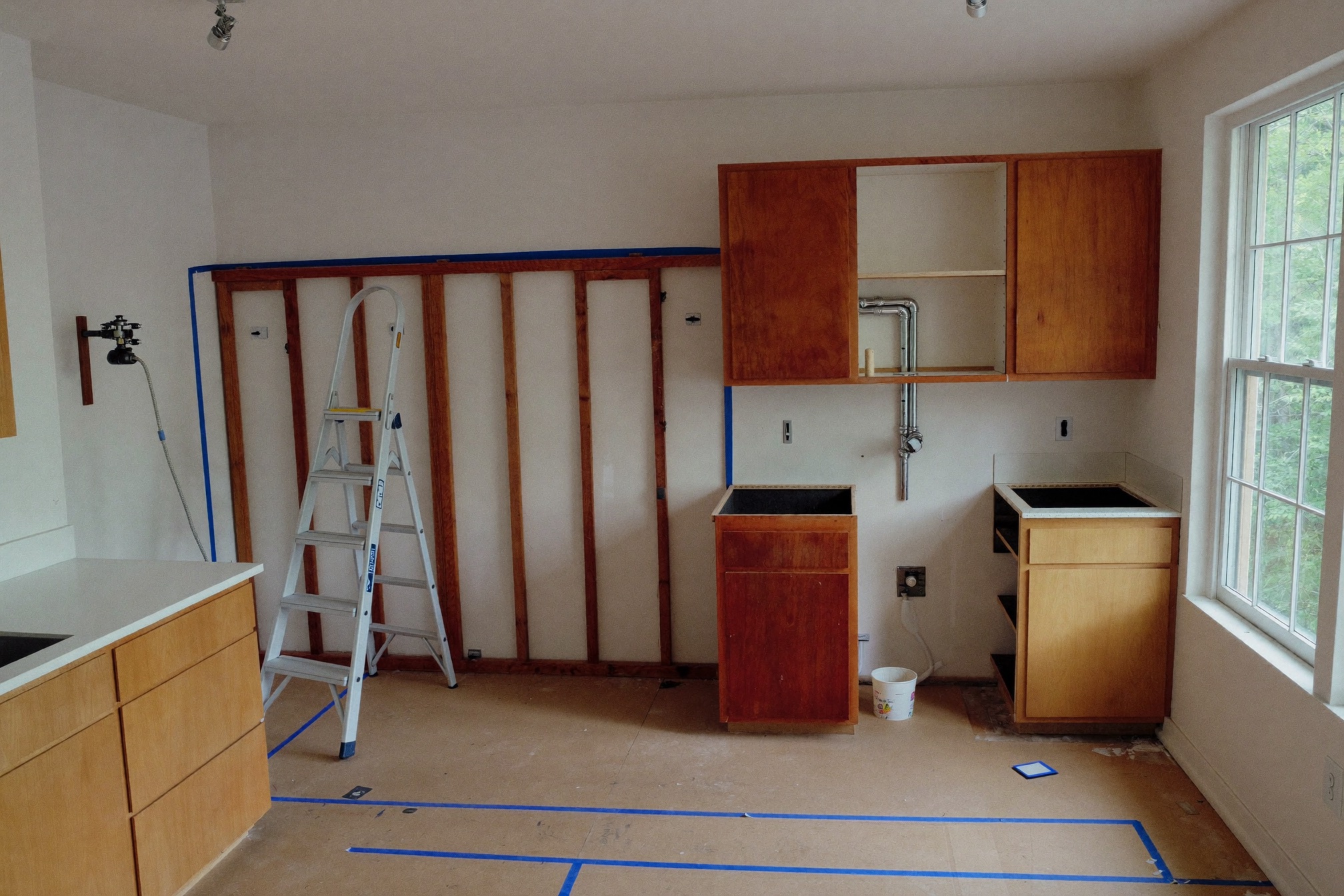 The same kitchen mid-remodel with cabinets removed and studs exposed