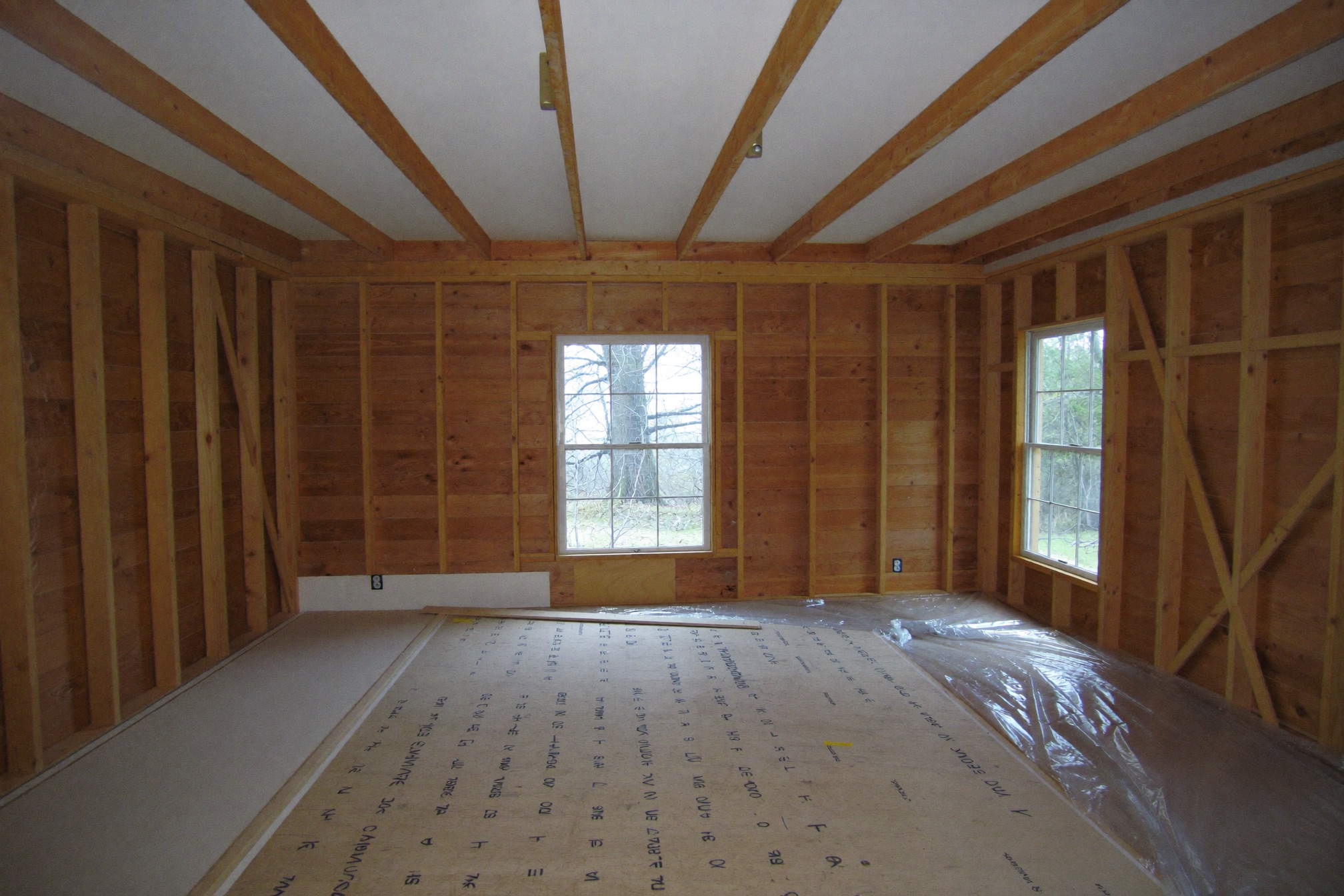 The same living room mid-remodel with framed stud walls and exposed subfloor